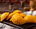 Empanadas de carne desmechada y papa crujientes servidas con ají y bebida refrescante.